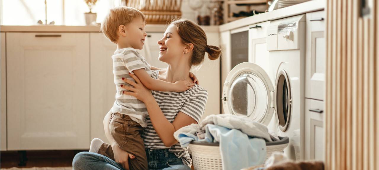 Una mujer con un niño mientras recoge la lavadora