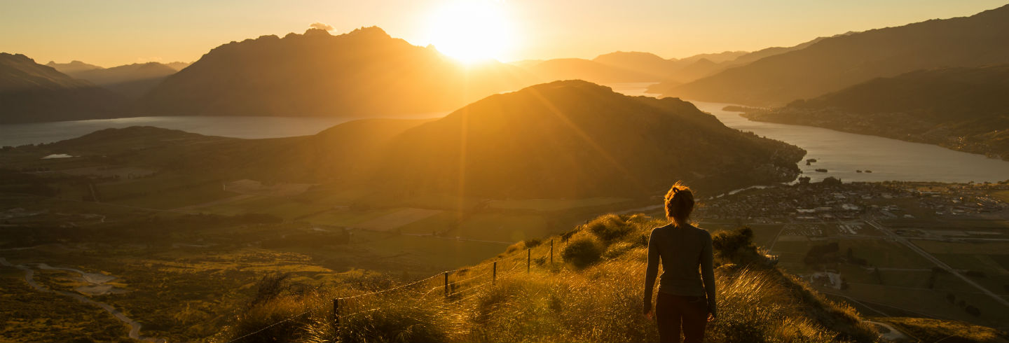 A woman looking out at the sunset over rolling hills