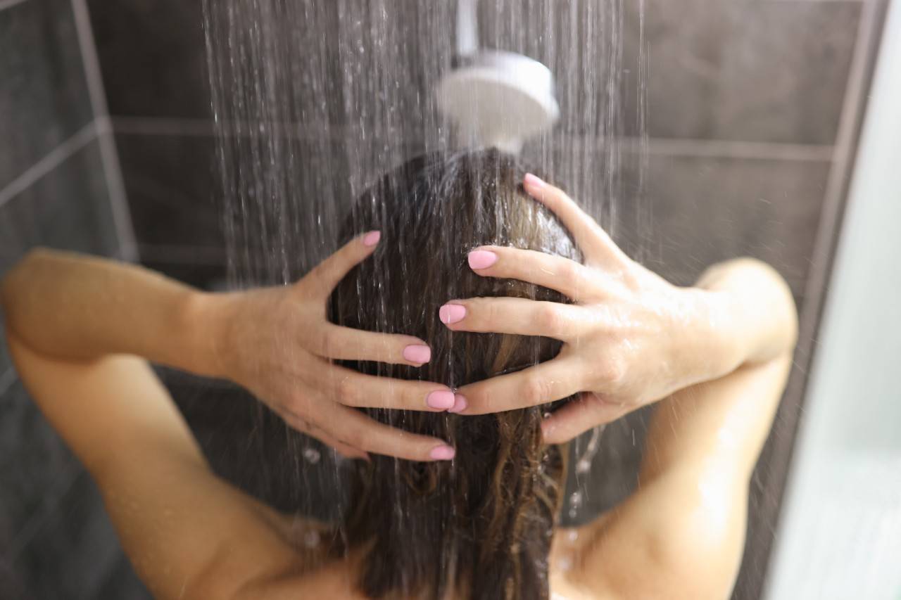 una mujer duchándose con agua calentada mediante energía geotérmica