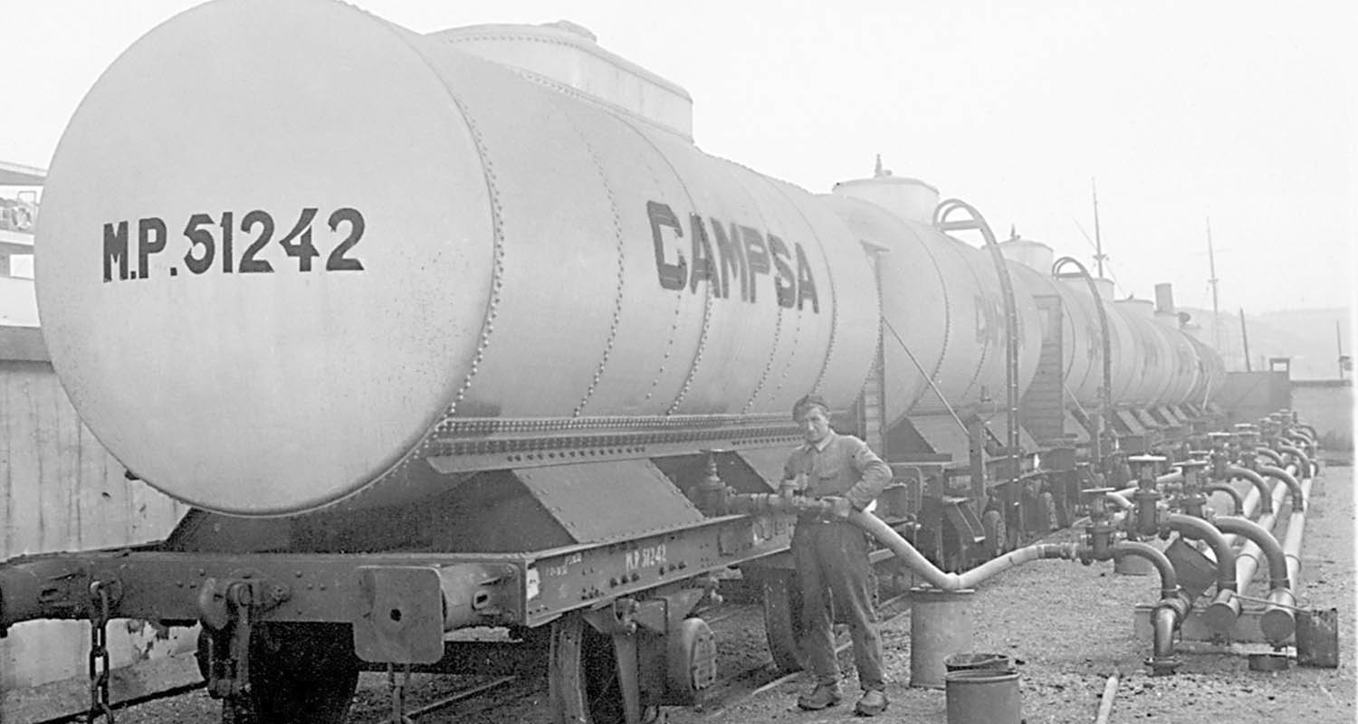Fotografía antigua de un empleado repostando en un vagón cisterna de Campsa 