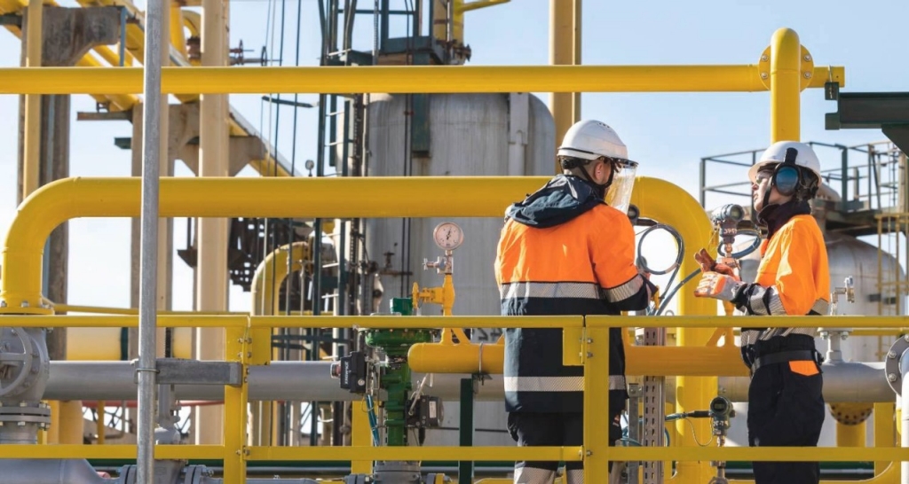 Empleados en complejo industrial con tuberías amarillas