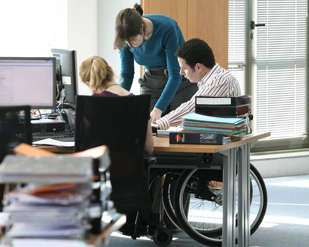 A man in a wheelchair in a meeting with coworkers at the Repsol Campus