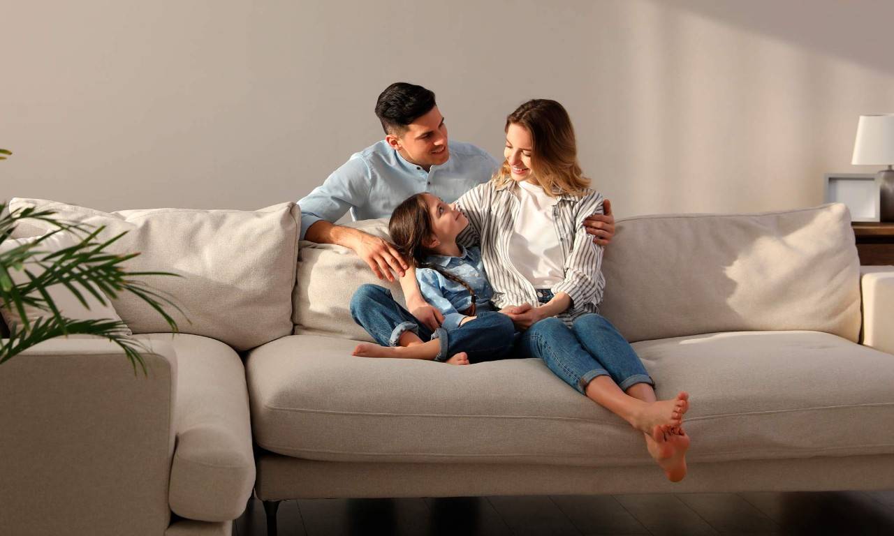 Familia con hija pequeña descansando en el sofá de la sala de estar