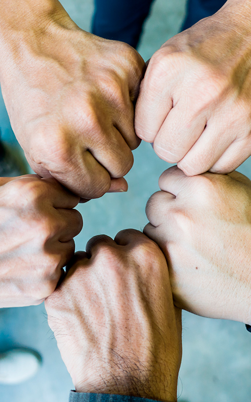 A group of people clench their fists together as a sign of a good work environment