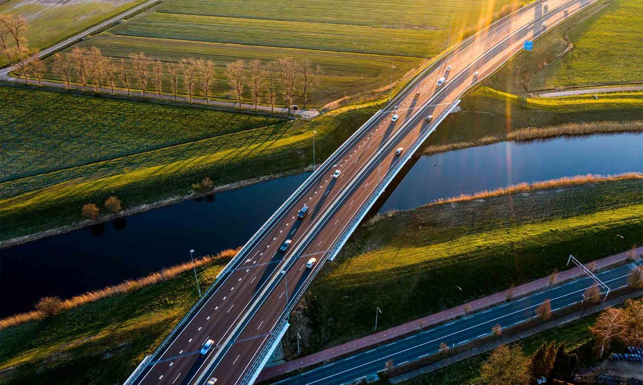 Imagen de una carretera sobre un río y paisajes verdes, como concepto de movilidad sostenible