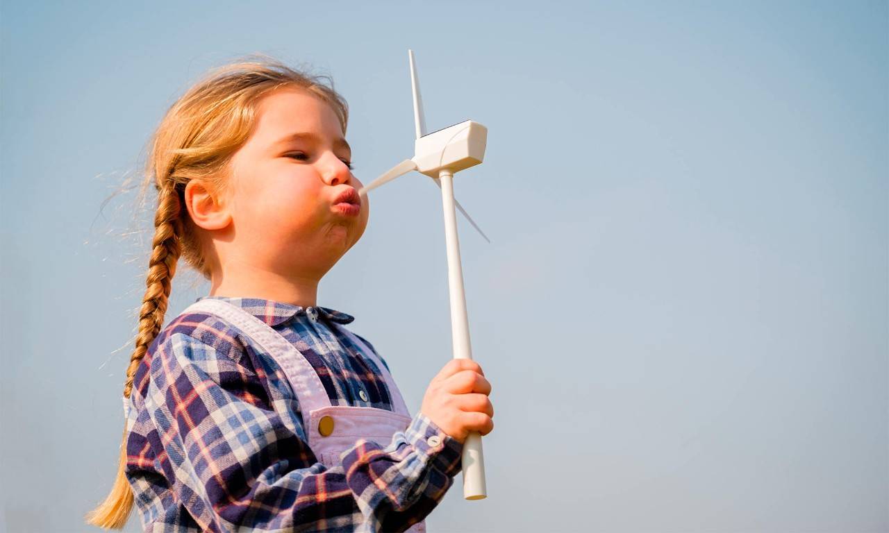 A girl blows a pinwheel representing sustainable energy