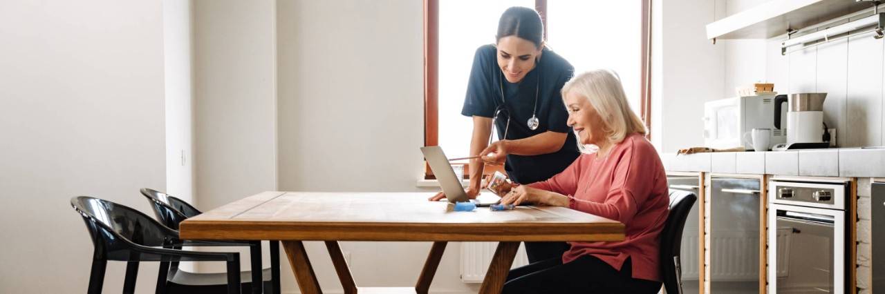 nurse teaching an elderly woman how to use a computer