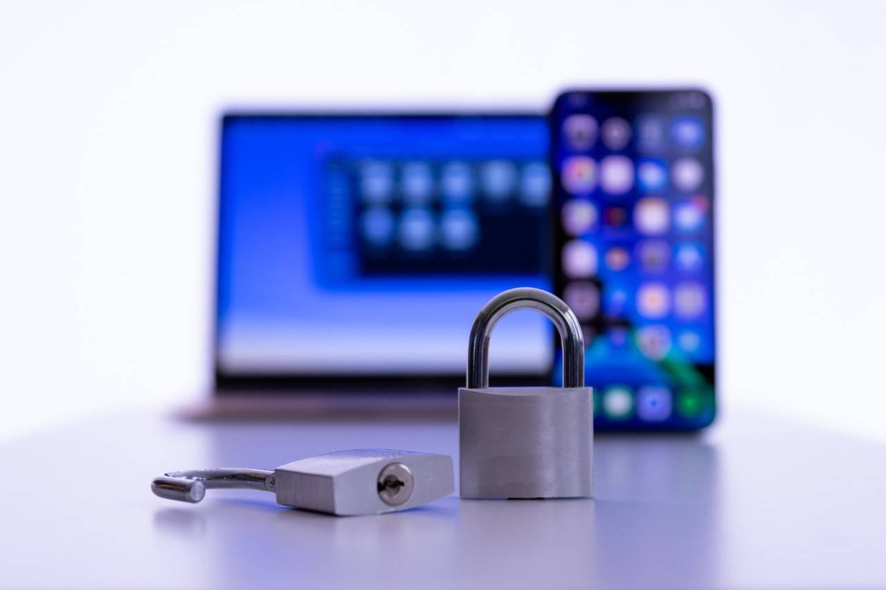 a padlock with a computer and cell phone in the foreground