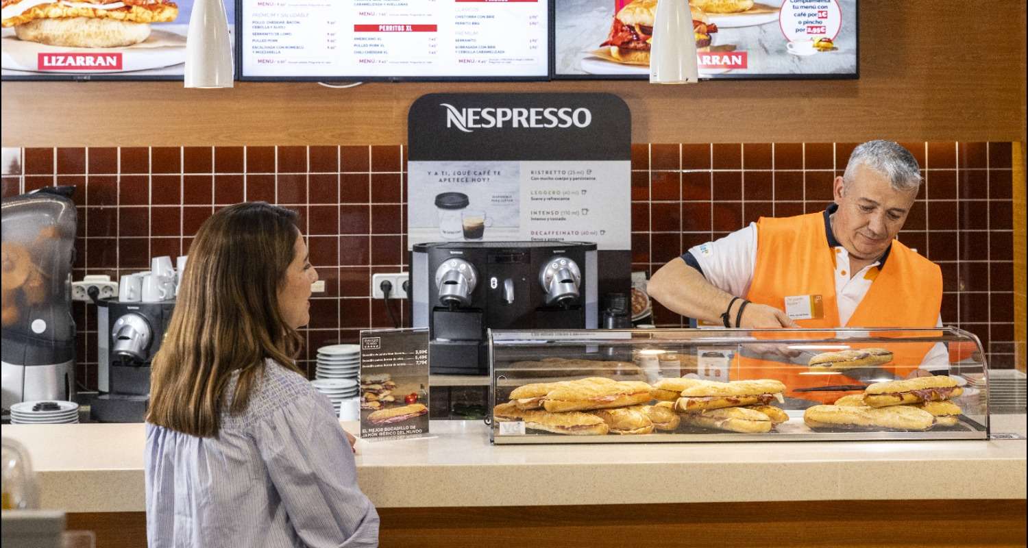 Mujer comprando bocadillos en estación Repsol