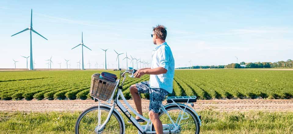 A boy on a bicycle in the countryside with a wind farm in the distance