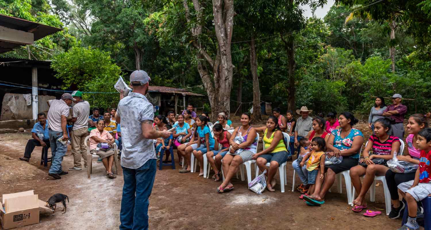 A man speaking to a group of people surrounded by a rainforest