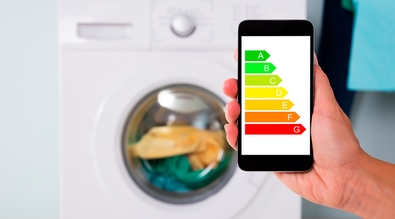 A smartphone showing the different energy efficiency label and a washing machine in the background