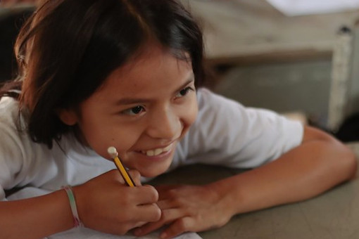 Una niña en el pupitre sonríe. Bolivia. 