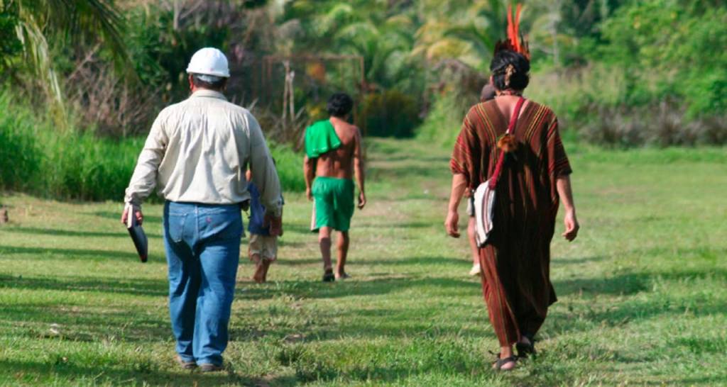 A Repsol employee walks next to an indigenous community member